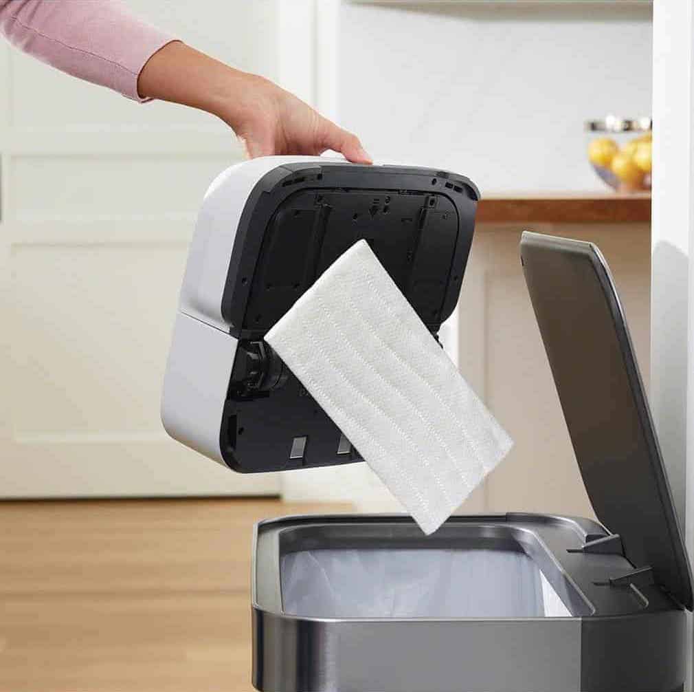 A person is using the Braava Jet M6 to put paper into a trash can.