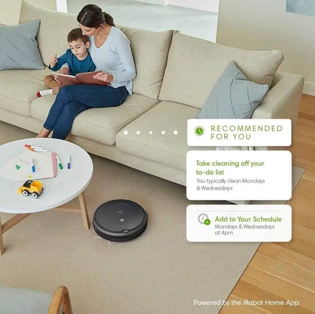 A woman and child are sitting on a couch with a Roomba 694, enjoying its convenience.