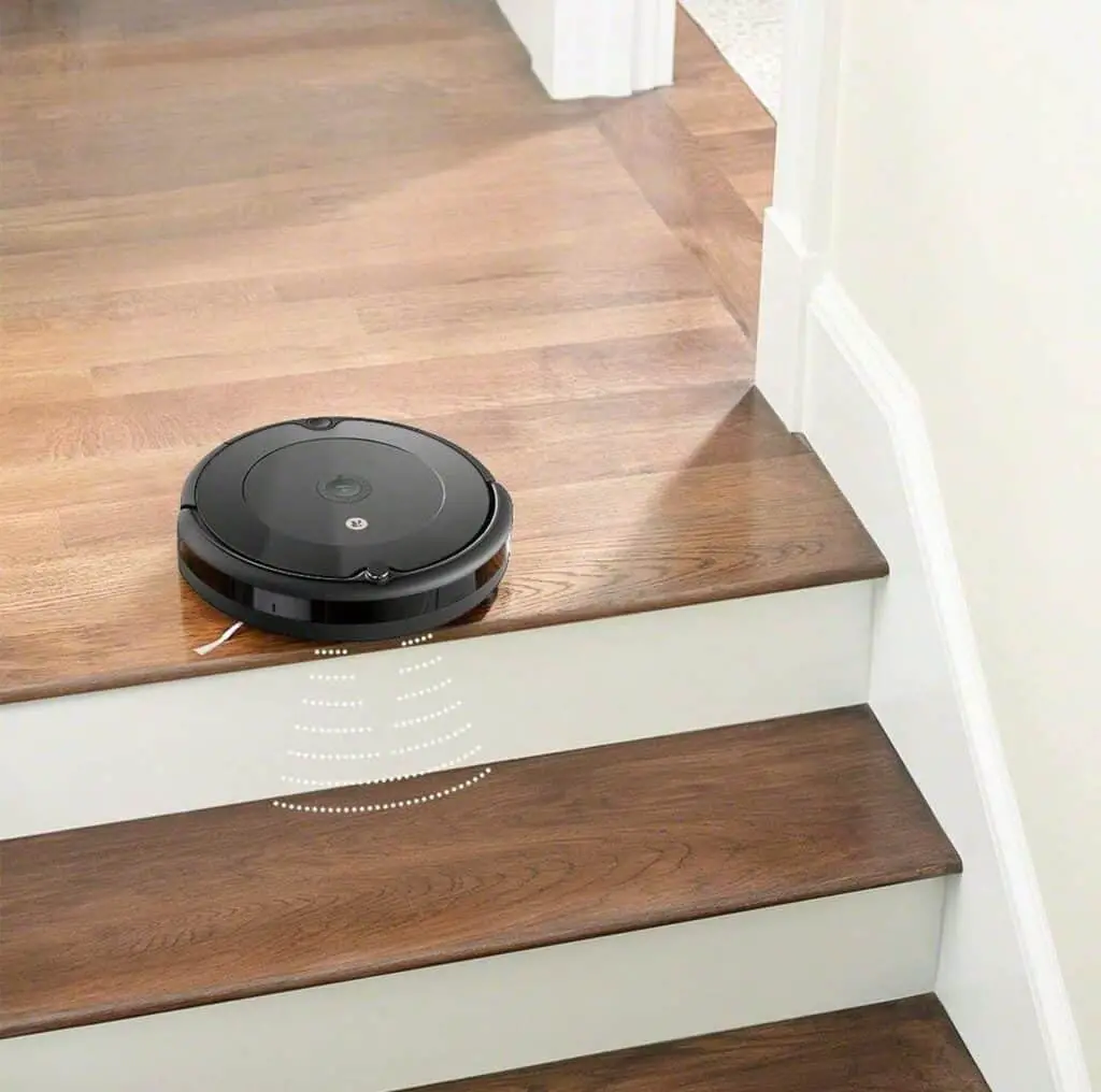 A roomba 694 robot vacuum diligently cleaning the stairs in a house.