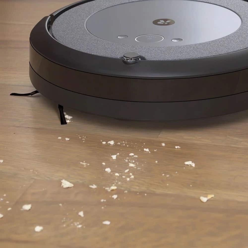 The Roomba Combo i5, a robotic vacuum cleaner, effortlessly glides across the smooth surface of a wooden floor. Experience the convenience and efficiency of the Roomba Combo i5 as it